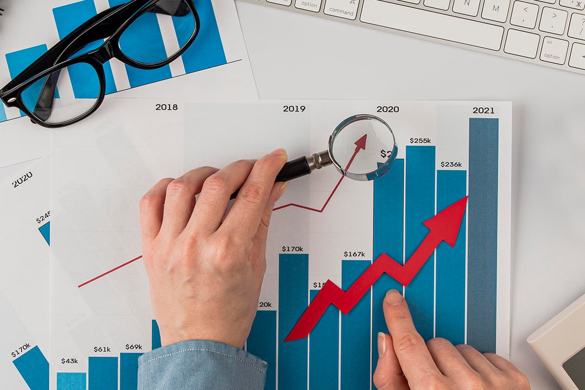 top-view-office-desk-with-growth-chart-hands-holding-magnifying-glass